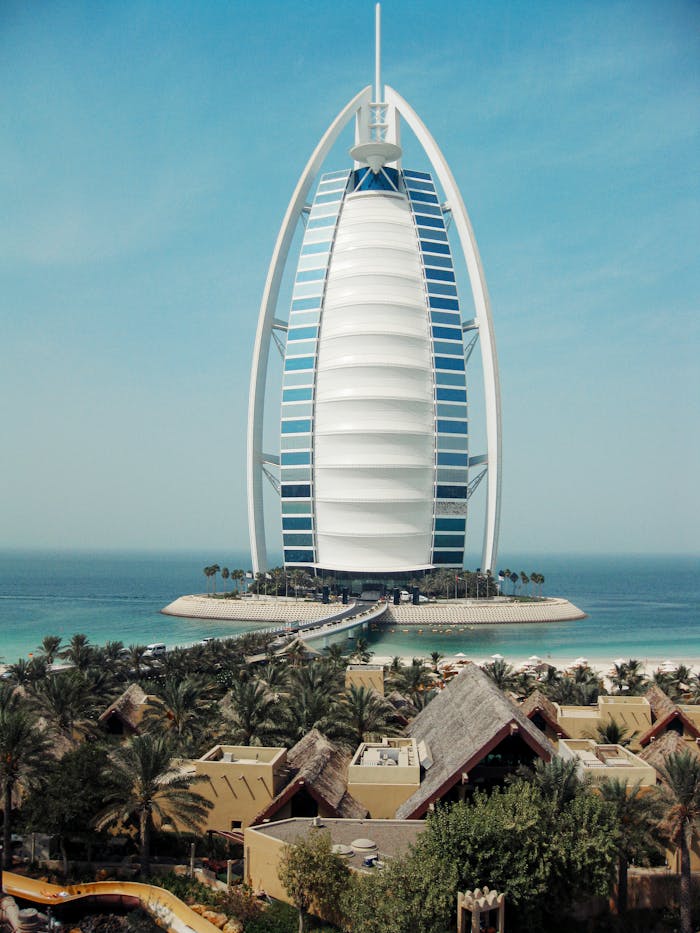 Iconic Burj Al Arab standing majestically on the Dubai waterfront under a clear blue sky.