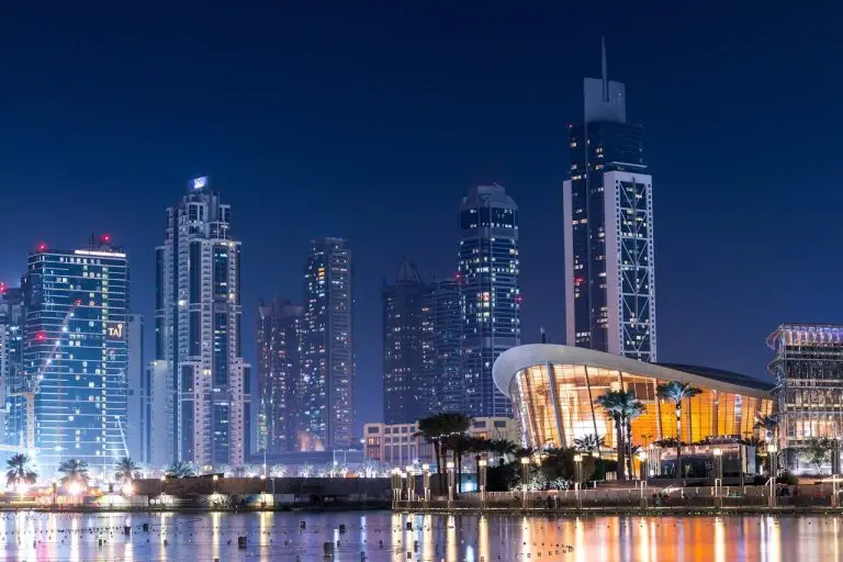 Stunning view of Dubai's illuminated skyline with modern skyscrapers reflecting on water at night.